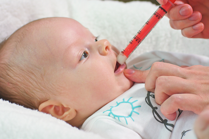 将注射器的尖端插入婴儿口中并释放药物。